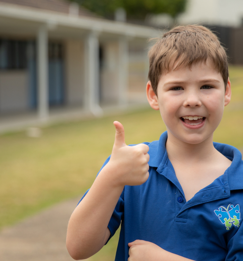 A kid looking at the camera and thumbing up